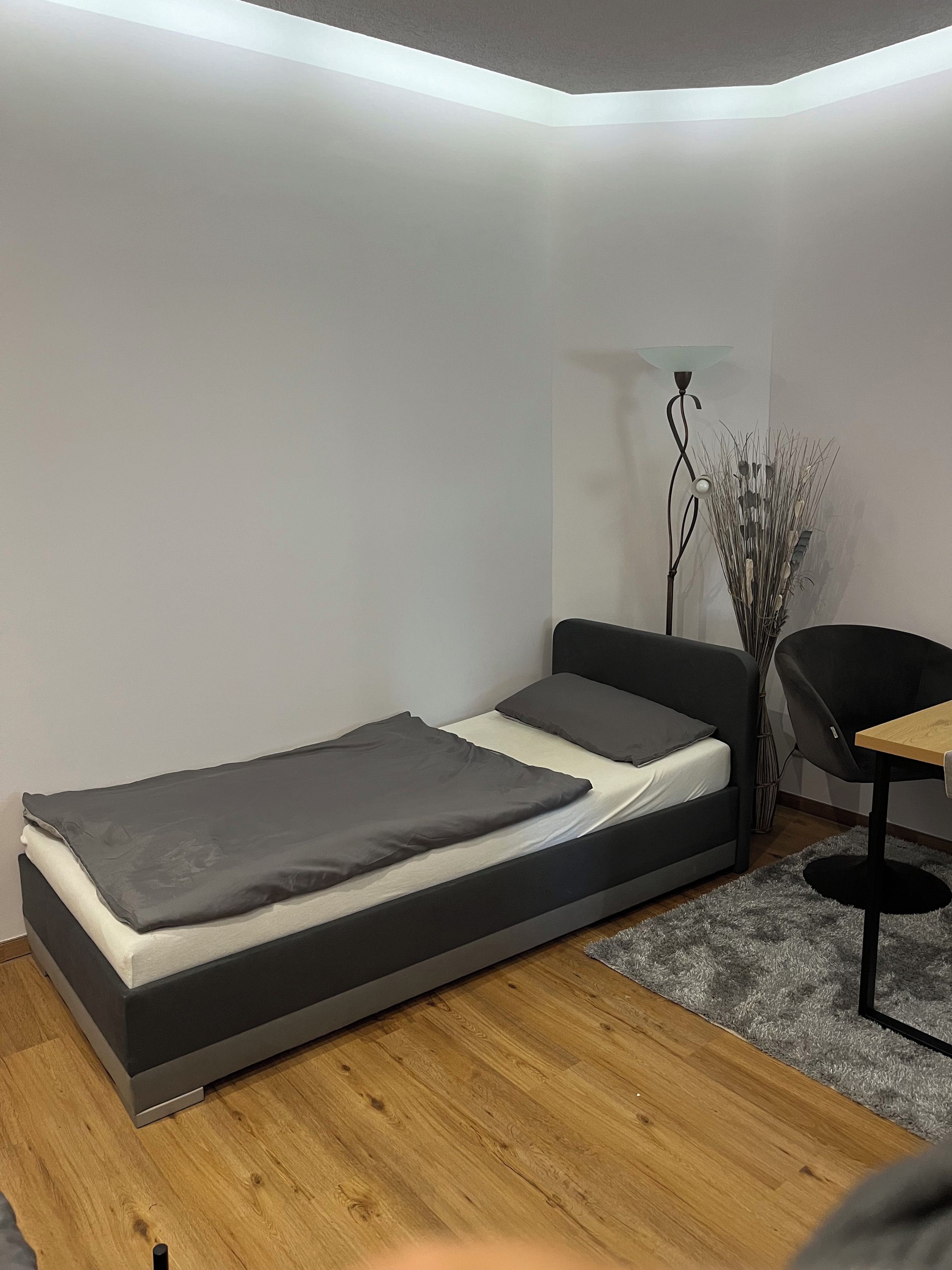 A compact room with a bed, a desk, and a chair.