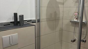 Eine begehbare, gläserne Dusche mit Handbrause und Wandarmatur.