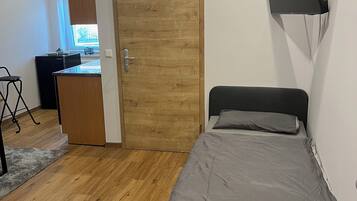 Ein Schlafzimmer mit einem Bett, einem Schreibtisch, einem Sessel und einem an der Wand befestigten Fernseher.