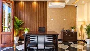 A conference room with a wooden panel wall, a ceiling fan, an air conditioning unit, and a checkered floor.