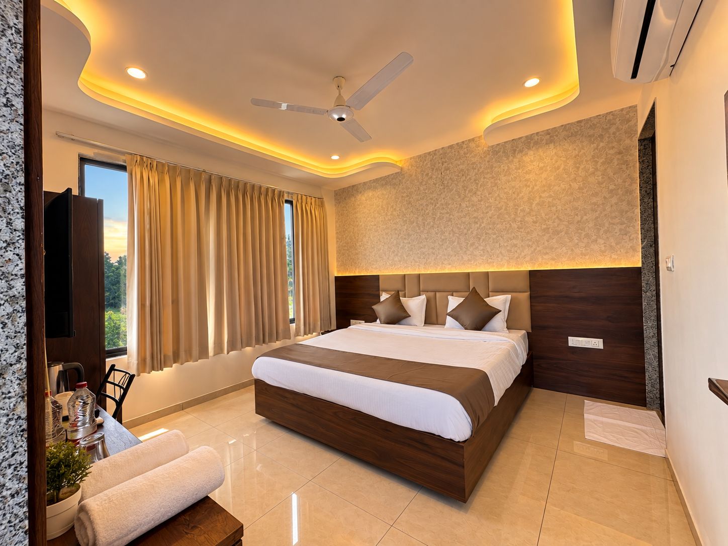 A modern hotel room with a large bed, a ceiling fan, and a view of the outdoors.
