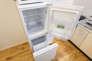 An open refrigerator with multiple shelves and a freezer compartment. - Villa Shimabara (Kyoto)