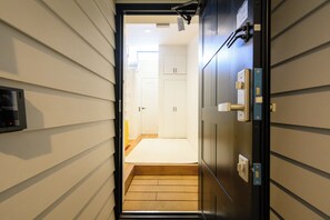 A hallway with a wooden floor leading to a room with a white door and a small window. - Villa Shimabara (Kyoto)