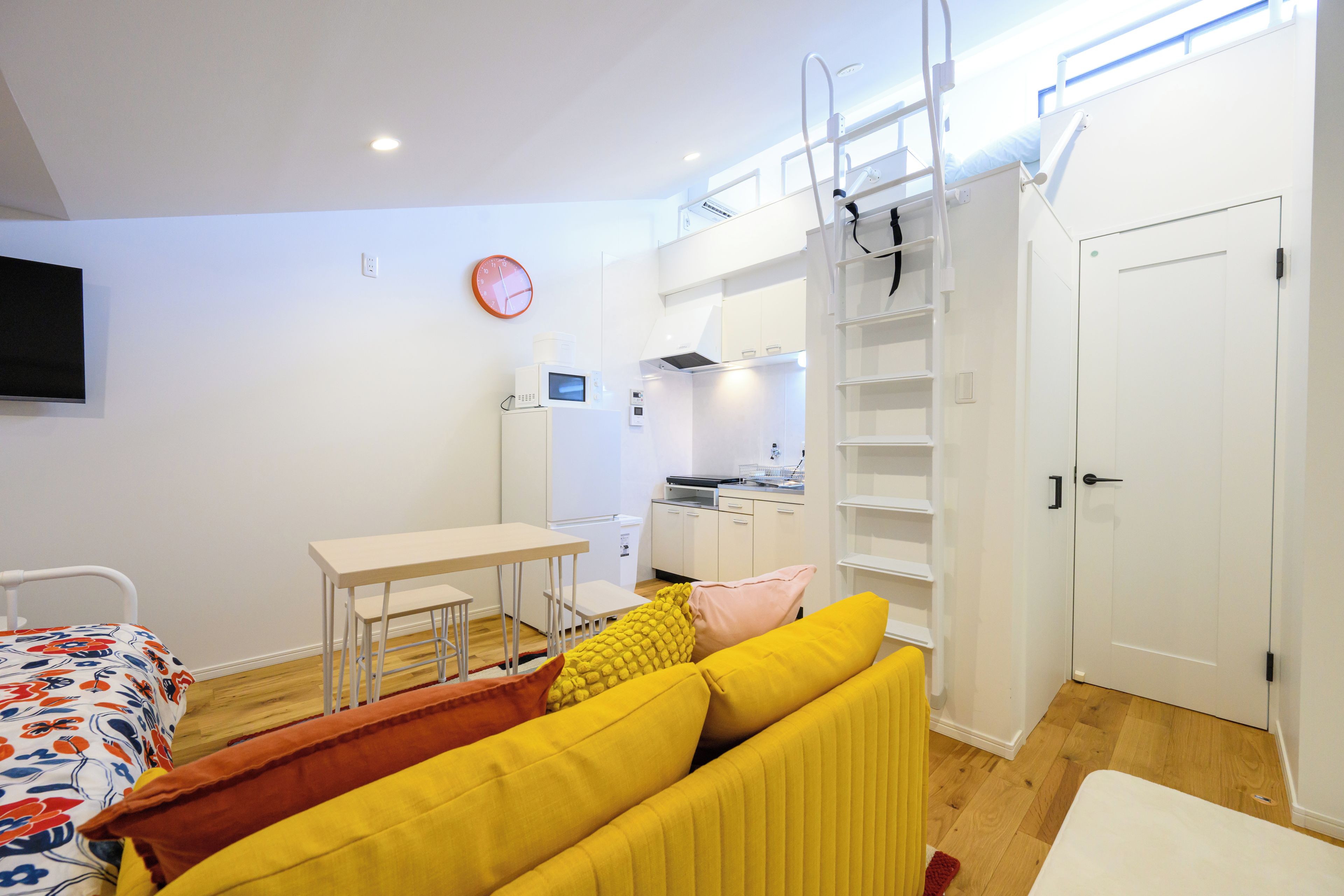 Un dormitorio moderno con cama, mesita de noche, kitchenette pequeño y armario.