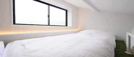 Un dormitorio con una cama individual, un ventanal grande y un radiador.
