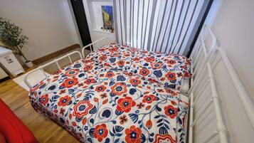 Ein Zimmer mit einem Bett, einem Heizkörper, einer Topfpflanze und einem Bild an der Wand.