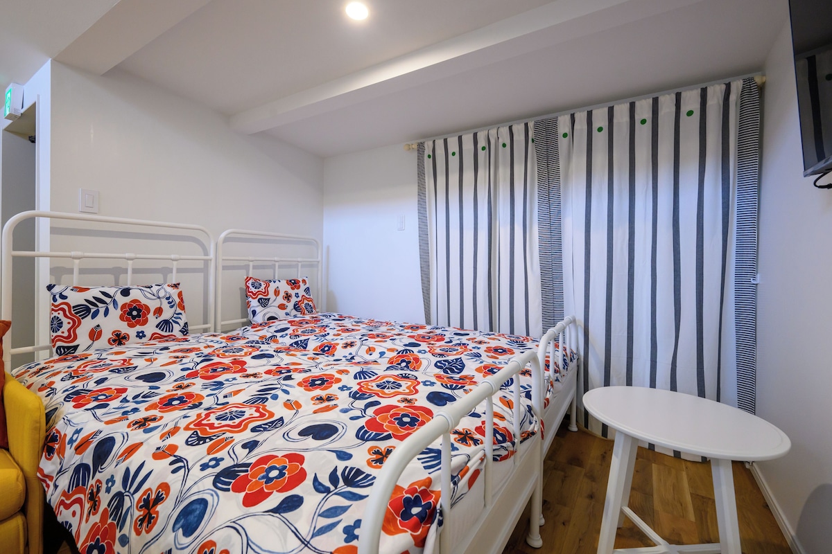 A bedroom with a bed, a bedside table, a chair, and a window with curtains.