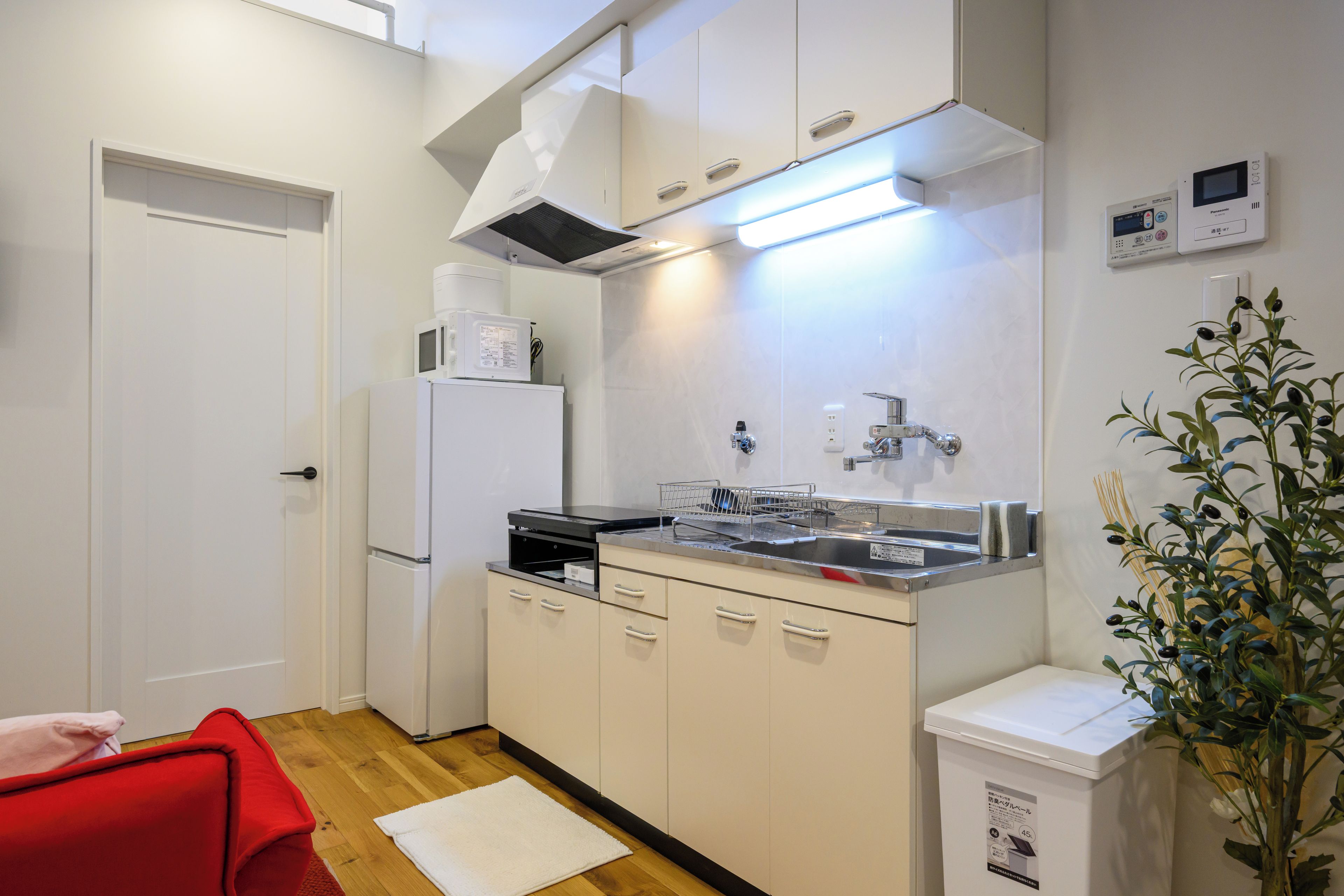 Una cocina compacta con horno integrado, pileta y refrigerador pequeño.