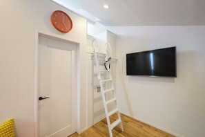 A room with a white door, a white ladder, a mounted television, and a clock on the wall. - Villa Shimabara (Kyoto)