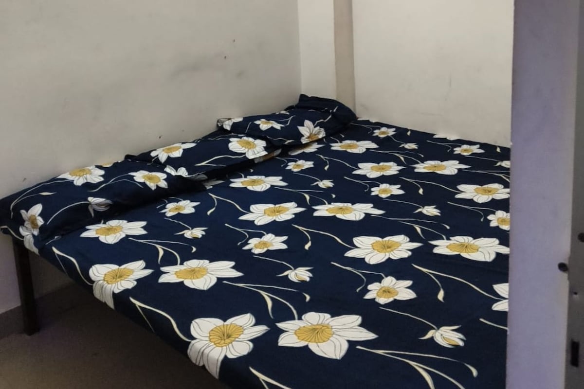 A small, single-bed room with a floral-patterned bedspread.
