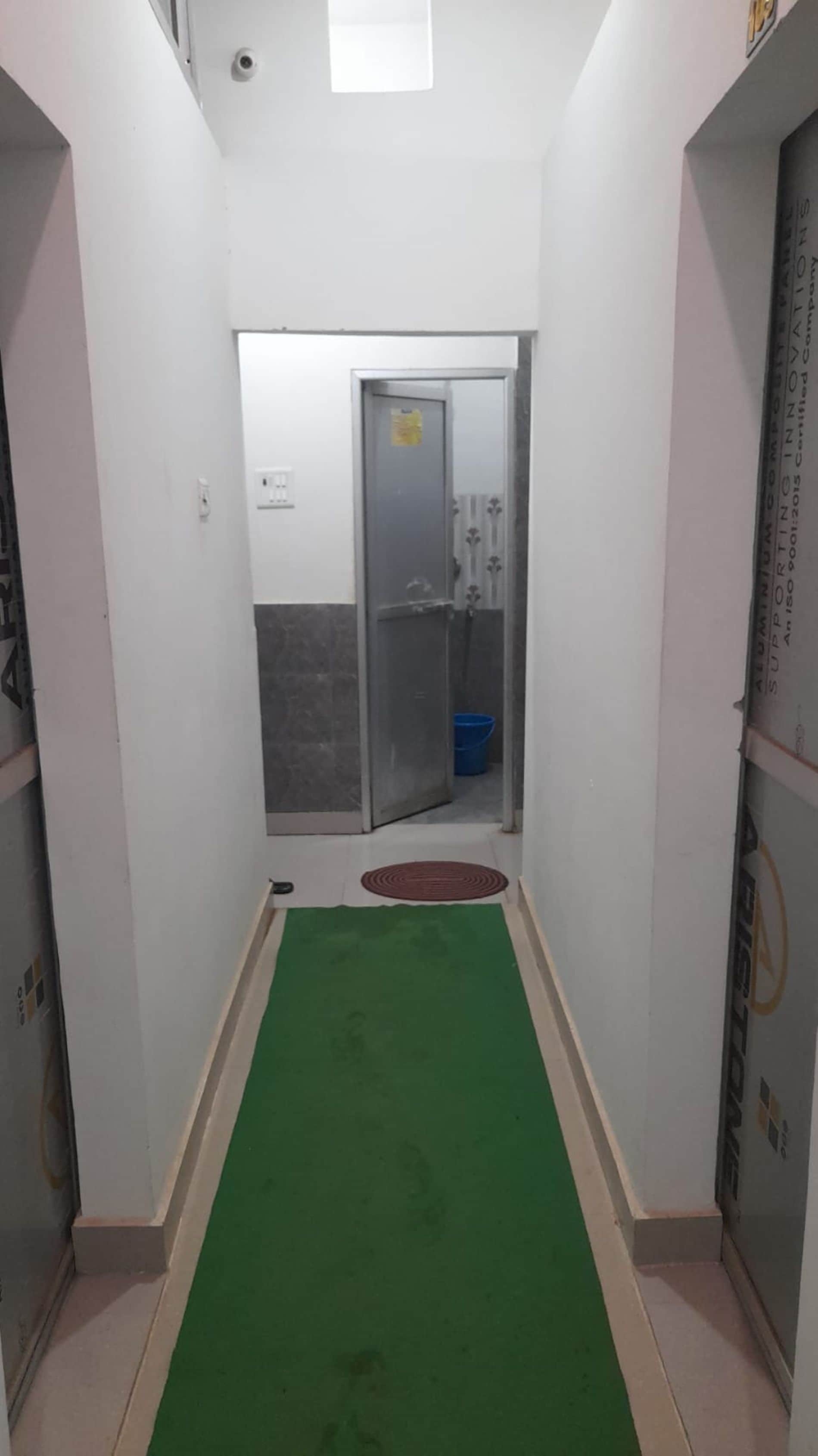 En smal hall med en grön matta som leder fram till en dörr med ett glasparti.