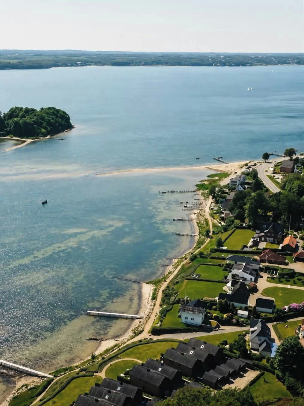 Ein Wohngebiet mit Häusern, einem Strand und einem Steg, der sich in ein großes Gewässer erstreckt.