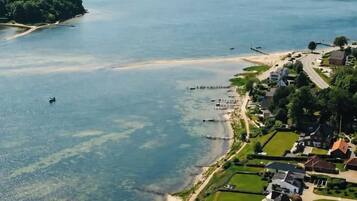 Ein Wohngebiet mit Häusern, einem Strand und einem Steg, der sich in ein großes Gewässer erstreckt.