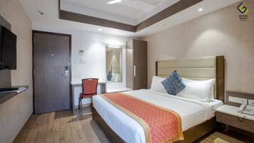 A hotel room with a bed, a desk, a chair, a wardrobe, and a mirror.