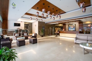 Un vestíbulo de hotel moderno con áreas de descanso, una recepción y una escalera.