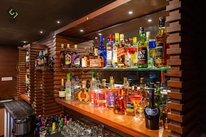 Zona de bar con múltiples estantes repletos de botellas de licores y vasos.