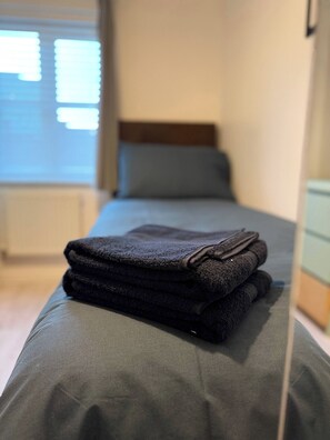 A neatly made bed with a folded towel on the side. - A&R Guest House - 2-bed Coach House, Bristol (Bristol)