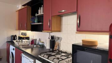 Cozinha compacta com fogão a gás, micro-ondas e máquina de lavar.