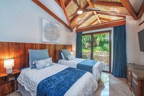 Een slaapkamer met twee bedden, een plafondventilator, een groot raam met gordijnen en een aan de muur bevestigde televisie.