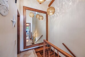 Ein Flur mit einem großen Spiegel, einer Holzhandläufe und dekorativen Wandleuchten.