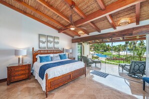 Ein Schlafzimmer mit einem hölzernen Bett, einem Nachttisch und Blick auf Pool und Garten.