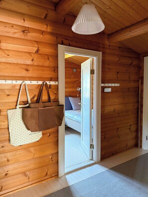 Ein Holzinnenraum mit einer Tür zu einem Schlafzimmer, einer hängenden Tasche und einem an der Wand befestigten Schild.