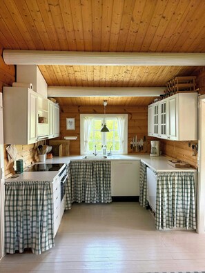 Cozinha compacta com armários de madeira, ilha central e cortinas xadrez.