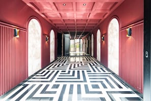 Un pasillo con piso de diseño geométrico, arcos y apliques en la pared.