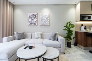 Una sala de estar moderna con un sofá, dos mesas auxiliares y una obra de arte en la pared.