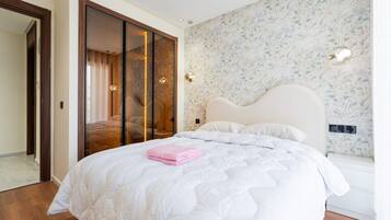A bedroom with a bed, a wardrobe, and a wall with a floral pattern.