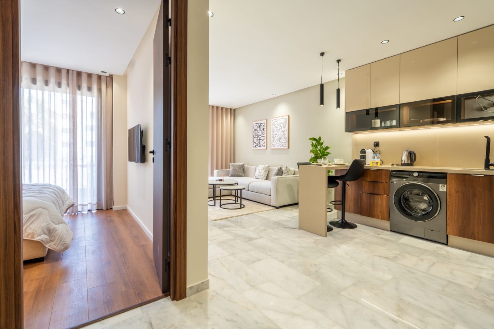 A modern apartment with a living area, a kitchen with a built-in washer, a sofa, and a dining table.