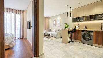 A modern apartment with a living area, a kitchen with a built-in washer, a sofa, and a dining table.