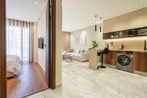 A modern apartment with a living area, a kitchen with a built-in washer, a sofa, and a dining table.