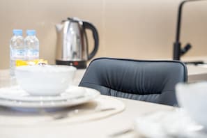 A table with a bowl of food, a kettle, and bottled water.