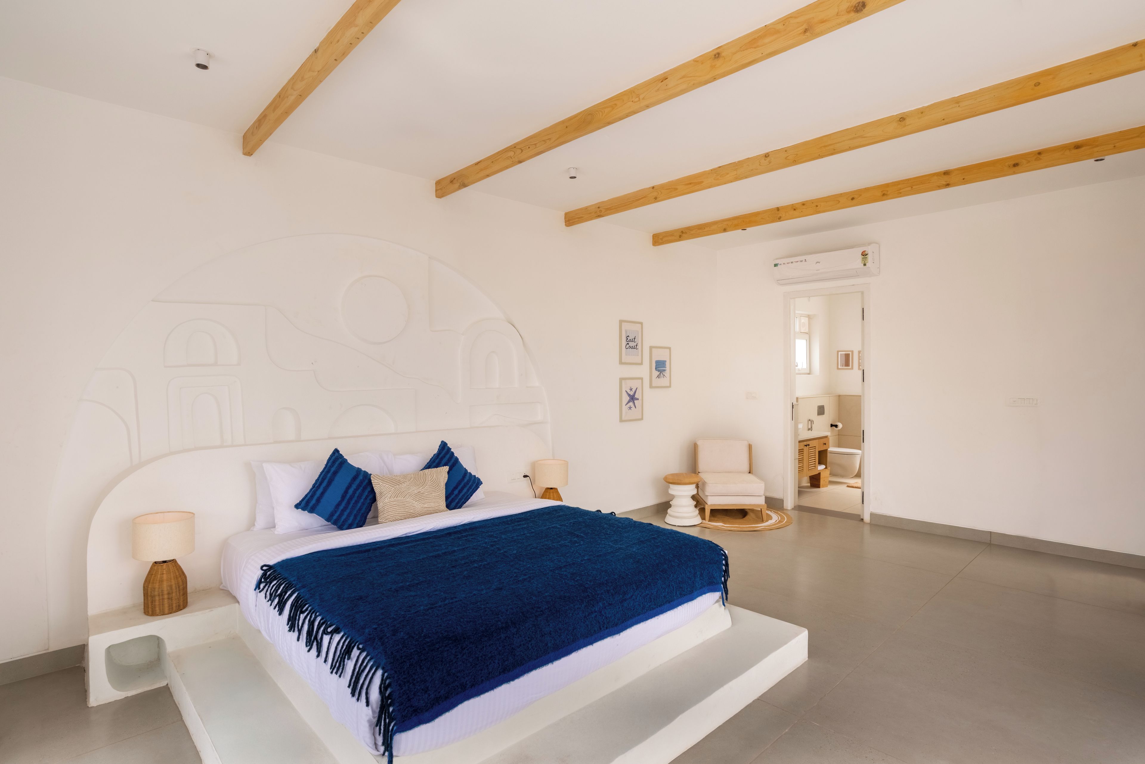Ein Schlafzimmer mit einem Bett, Nachttischen, einem Nachtschränkchen, einer Wand-Klimaanlage und einer Tür zu einem Badezimmer.