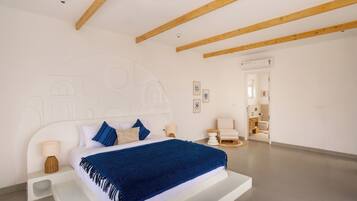 Ein Schlafzimmer mit einem Bett, Nachttischen, einem Nachtschränkchen, einer Wand-Klimaanlage und einer Tür zu einem Badezimmer.