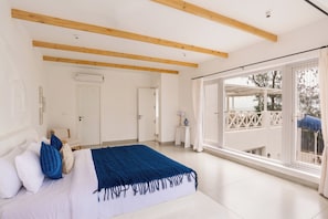 Un dormitorio con una cama grande, vistas al exterior y un balcón.