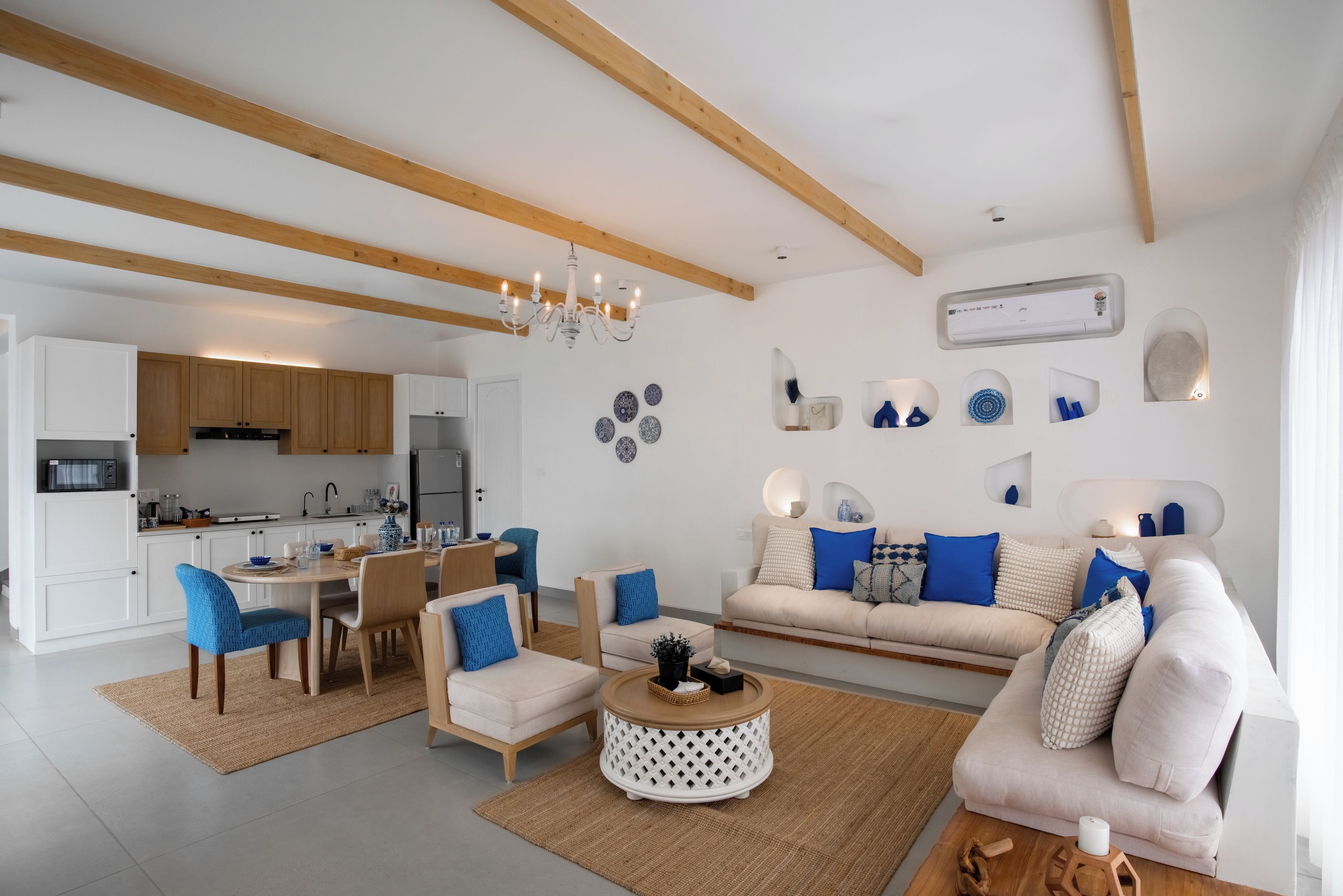 A modern living room with a sofa, chairs, a coffee table, and a dining area with a table and chairs.