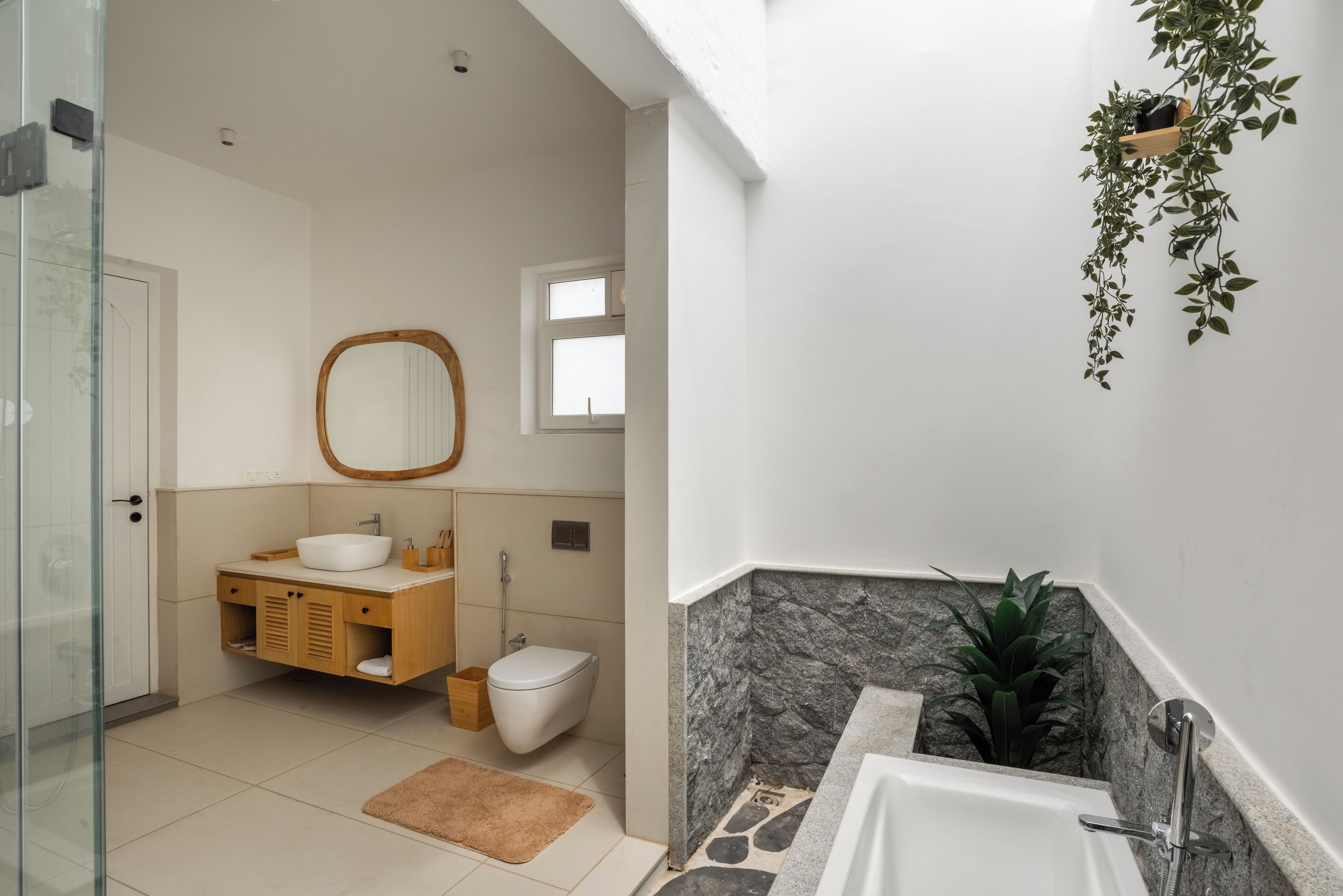A modern bathroom with a freestanding bathtub, a wooden vanity, a toilet, and a mirror.