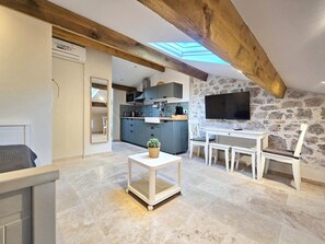 A modern interior with a dining area, kitchen, and a stone wall. - 16097522 FRGK 5-Apartment Building - Downtown Cannes - Conference Special - 47 rue Meynadier (Cannes)