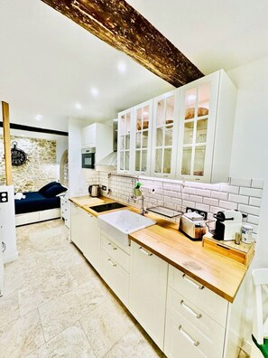 A modern kitchen with white cabinets, a wooden countertop, and a stone backsplash. - 16097522 FRGK 5-Apartment Building - Downtown Cannes - Conference Special - 47 rue Meynadier (Cannes)