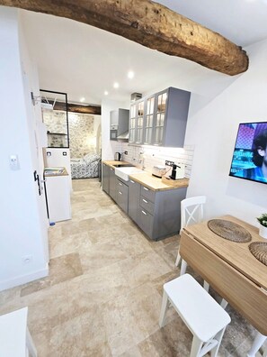 A modern kitchen with grey cabinets, a wooden dining table, and a television mounted on the wall. - 16097522 FRGK 5-Apartment Building - Downtown Cannes - Conference Special - 47 rue Meynadier (Cannes)