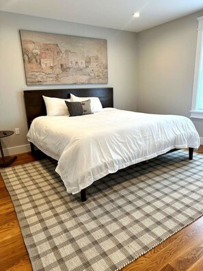 A bedroom with a large bed, a headboard, a checkered rug, and a painting on the wall. - Walkable Village 5BR Home, 2 Full Kitchens, King Beds - Great for Groups. (Montgomery)
