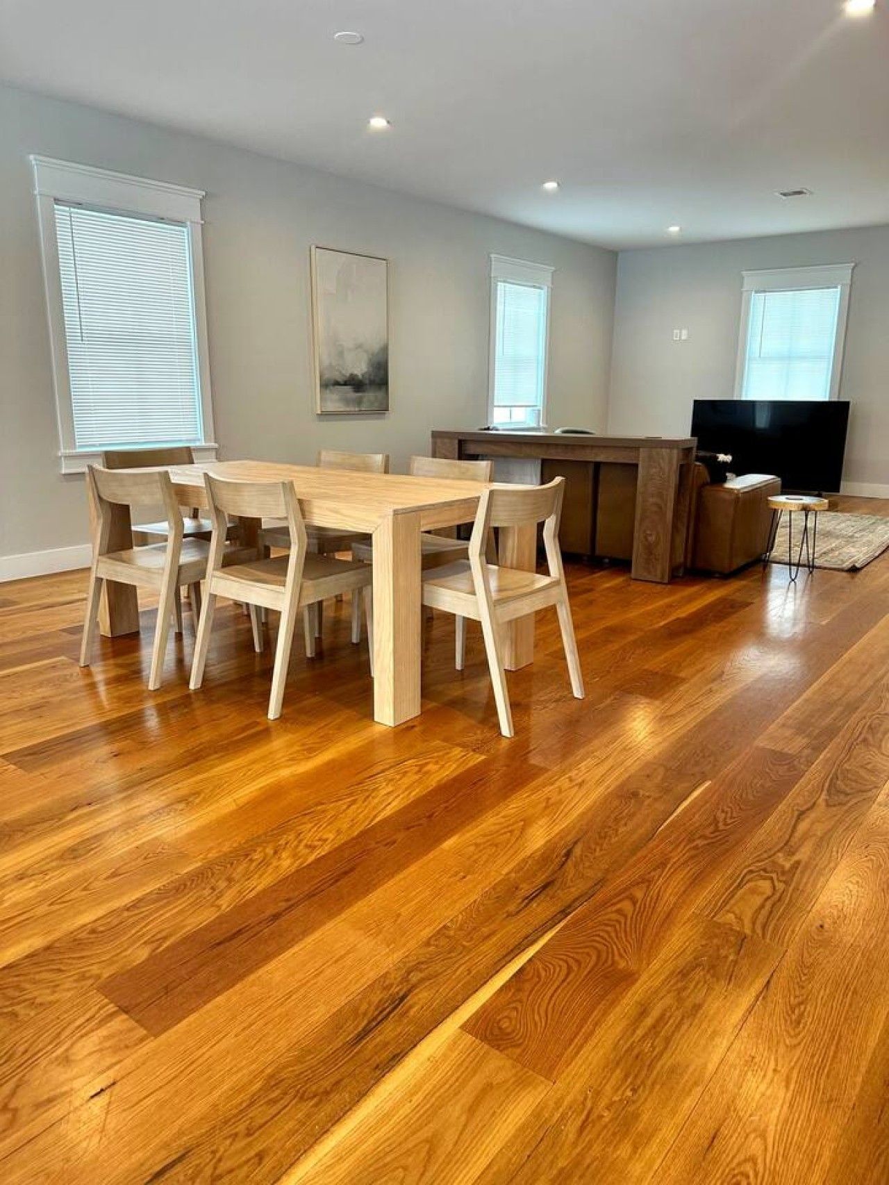 A dining area with a wooden table and chairs, a television, and a small side table.