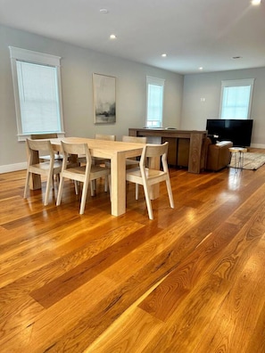 A dining area with a wooden table and chairs, a television, and a small side table.
