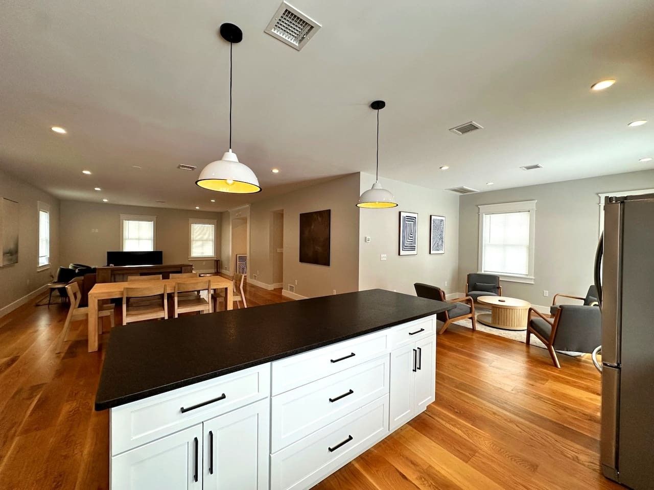 A modern kitchen with a black countertop, white cabinets, and pendant lighting.