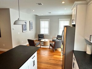 A modern kitchen with a dining area, wooden flooring, and a refrigerator. - Walkable Village 5BR Home, 2 Full Kitchens, King Beds - Great for Groups. (Montgomery)