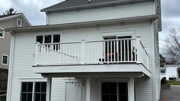 A two-story residential building with a balcony, a front door, and a small porch area.