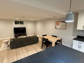 A modern kitchen with a dining area, a large flat-screen TV, and a built-in oven.