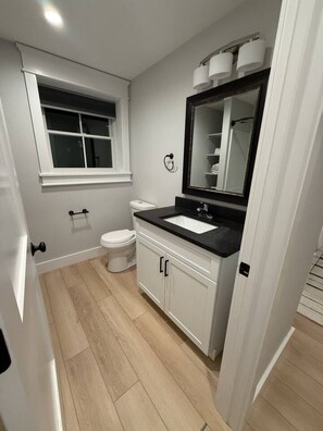 A modern bathroom with a toilet, sink, and mirror.